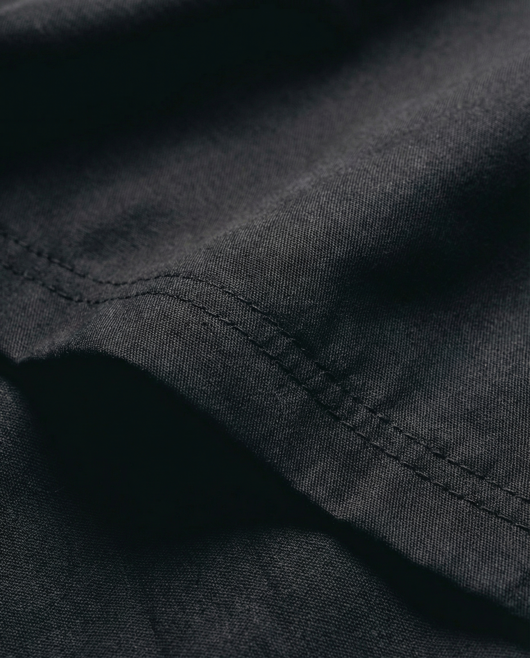 Close-up of black fabric with visible stitching. Fabric texture detail of Porsche Racing Jacket showing durable material and quality construction
