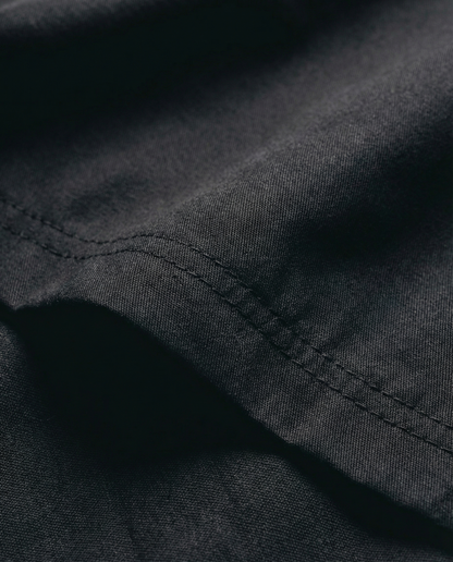 Close-up of black fabric with visible stitching. Fabric texture detail of Porsche Racing Jacket showing durable material and quality construction
