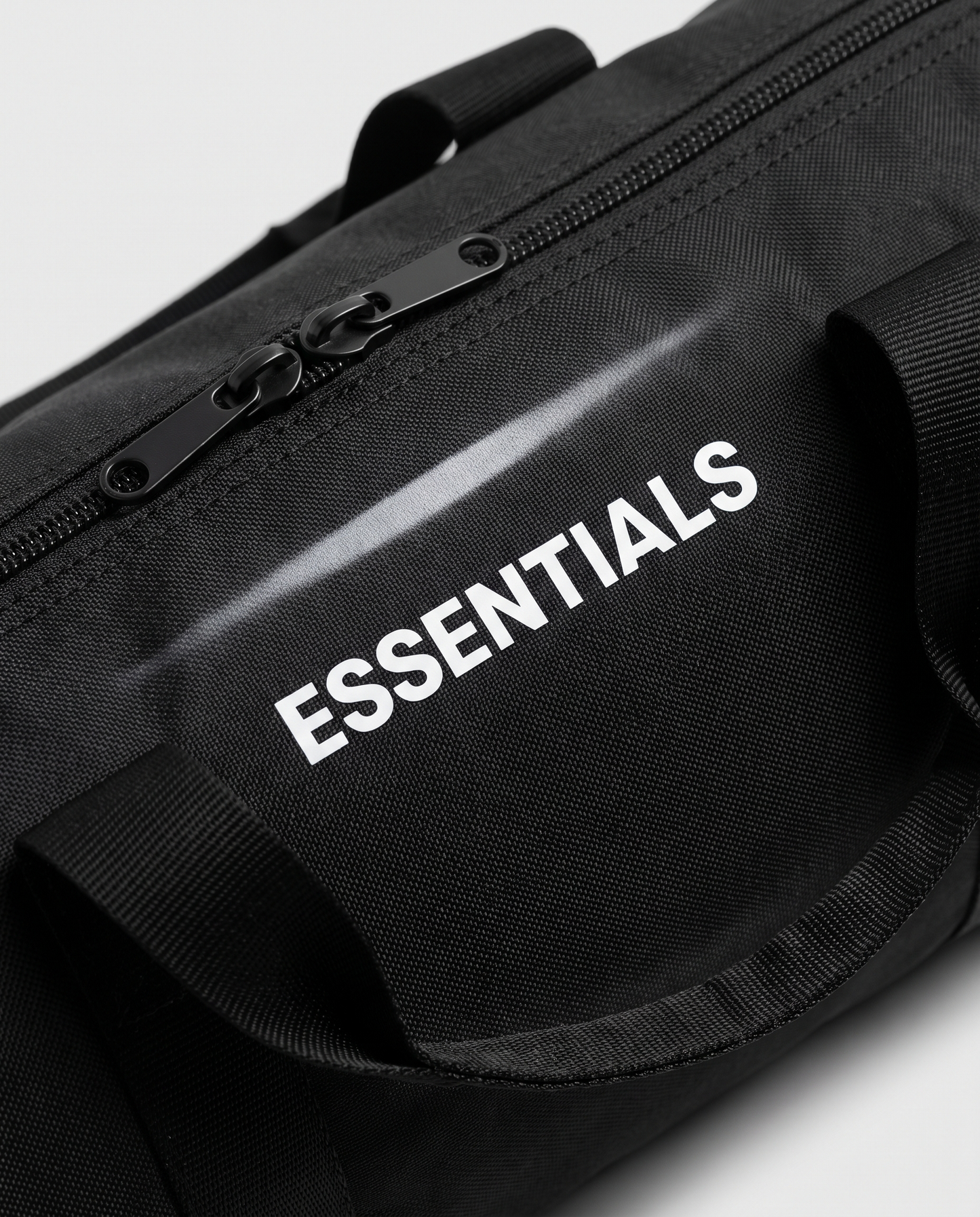 Just the Essentials duffle bag — macro detail of ESSENTIALS print and zipper
