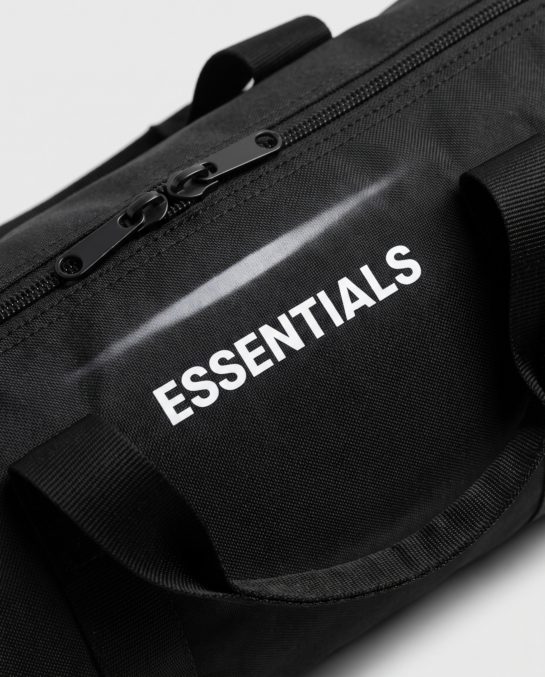 Just the Essentials duffle bag — macro detail of ESSENTIALS print and zipper
