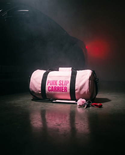 Pink Slip Carrier gym bag under pink glow on dark floor with keys